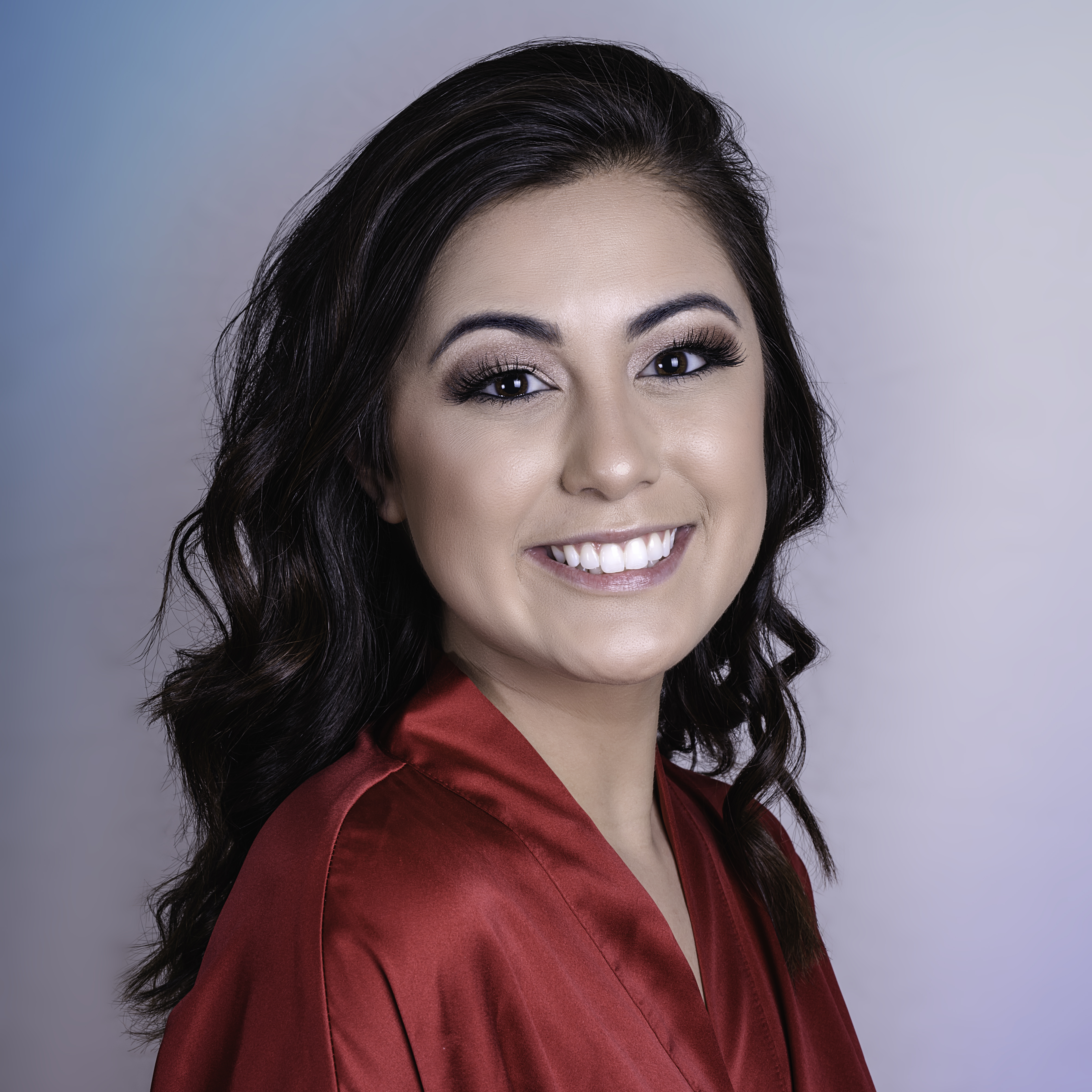 An attractive brunette with wavy hair wearing a red robe