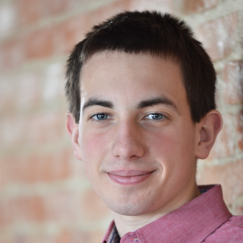 photo of a handsome young man in a dress shirt in front of a back wall